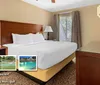 The image shows a hotel room with a large bed a nightstand with a lamp and windows promoting amenities like an on-site restaurant indoor pool playground and mini-golf with a Busch Gardens shuttle available