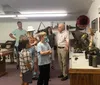 A group of people including children and adults are looking at exhibits inside a museum or gallery with one man appearing to explain something to the group