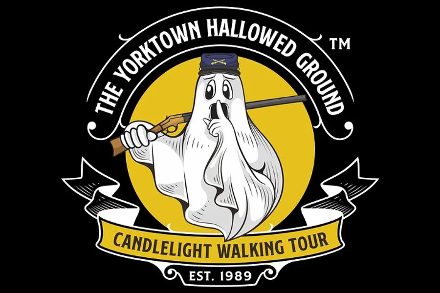 The image shows a logo for The Yorktown Hallowed Ground Candlelight Walking Tour, featuring a cartoonish ghost wearing a hat, holding a rifle, and set against a yellow background, with the text indicating the tour has been established in 1989.