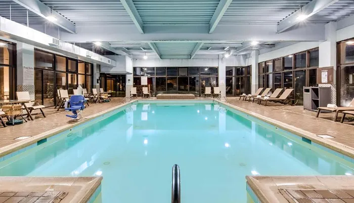 The image shows an indoor swimming pool area with lounge chairs and facilities typically found in a hotel or recreational center