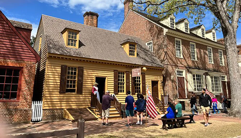 Visitors explore a historical colonial-era street with traditional architecture including a prominently featured yellow wooden building