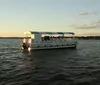 A ferry named Jamestown Discovery is cruising on the water with passengers on board during what appears to be late afternoon