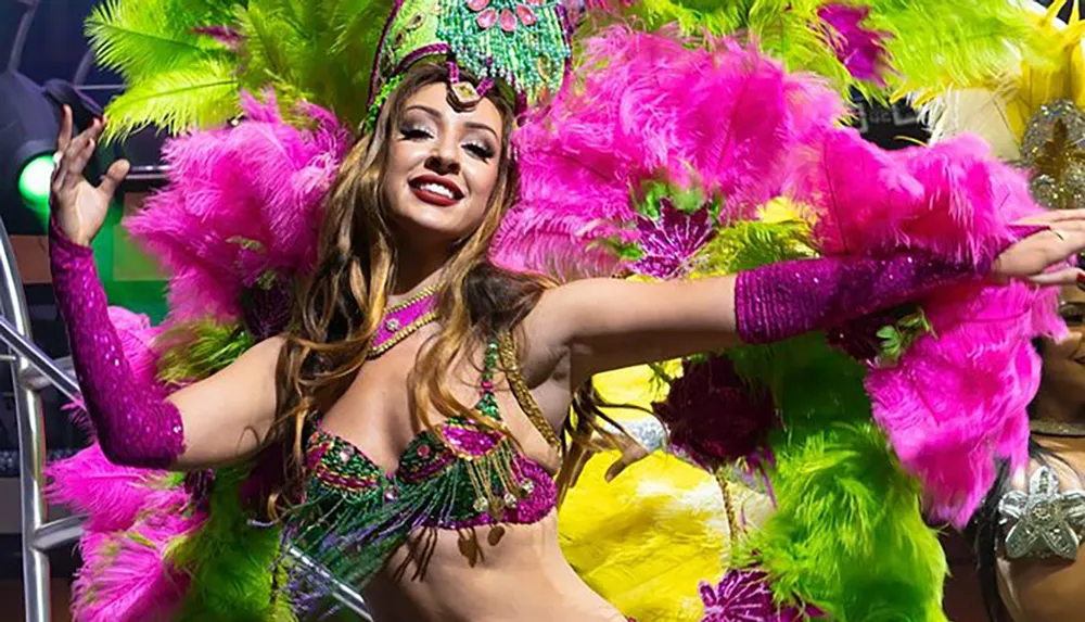 A performer in a vibrant feathered carnival costume is smiling as she dances