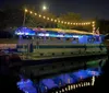 A group of people are enjoying a festive outdoor gathering with colorful lights at dusk