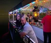 A group of people are enjoying a festive outdoor gathering with colorful lights at dusk