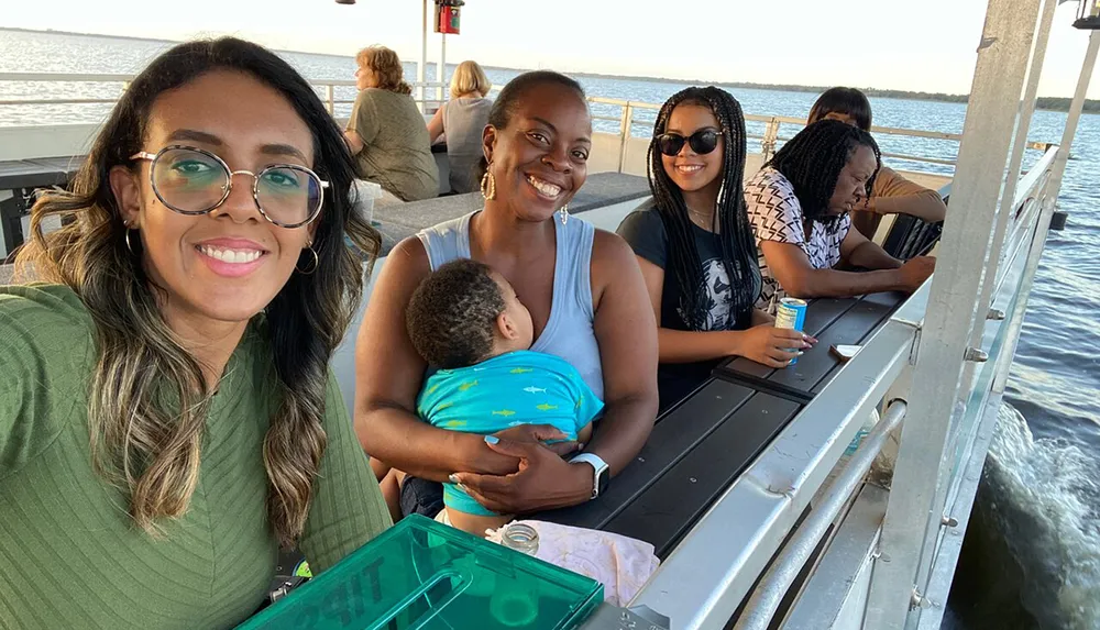 A group of people featuring a woman taking a selfie are enjoying a boat ride on a sunny day