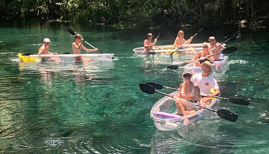 A group of people is leisurely kayaking in clear water using transparent kayaks.