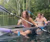 A group of individuals is kayaking in clear water with one person in a transparent kayak revealing the underwater view