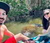 A smiling man and woman are enjoying kayaking together with a manatee visible in the water near them