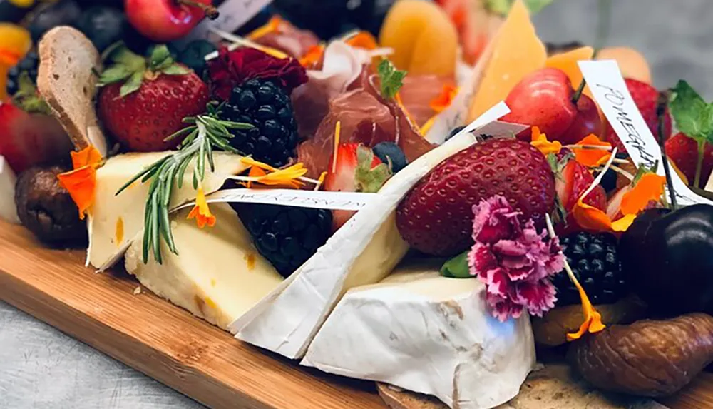 The image showcases a gourmet cheese board adorned with an assortment of fresh fruits nuts and edible flowers creating an inviting and colorful culinary presentation