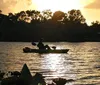 Two people are enjoying a kayak ride on calm waters during a warm golden hour