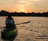 Two people are enjoying a kayak ride on calm waters during a warm golden hour