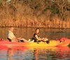 Two people are enjoying a kayak ride on calm waters during a warm golden hour