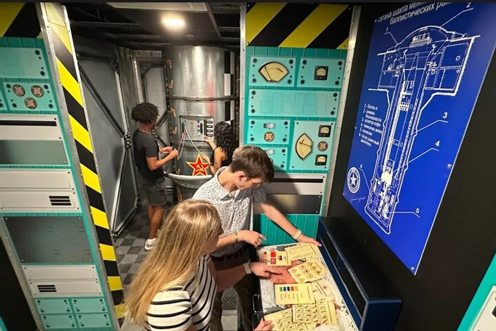 A group of people are engaging in what appears to be an escape room challenge surrounded by themed decorations that simulate a technical or possibly spacecraft environment