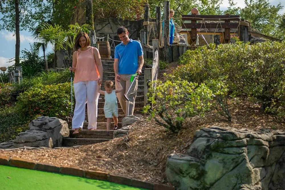 A family is enjoying a game of mini-golf on a sunny day at a well-landscaped course