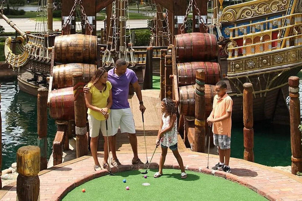 A family is enjoying a game of miniature golf together at a pirate-themed course
