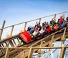 A group of excited riders are experiencing a thrilling descent on a wooden roller coaster