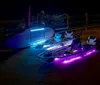 People are kayaking at night with their vessels illuminated by bright colorful underwater lights