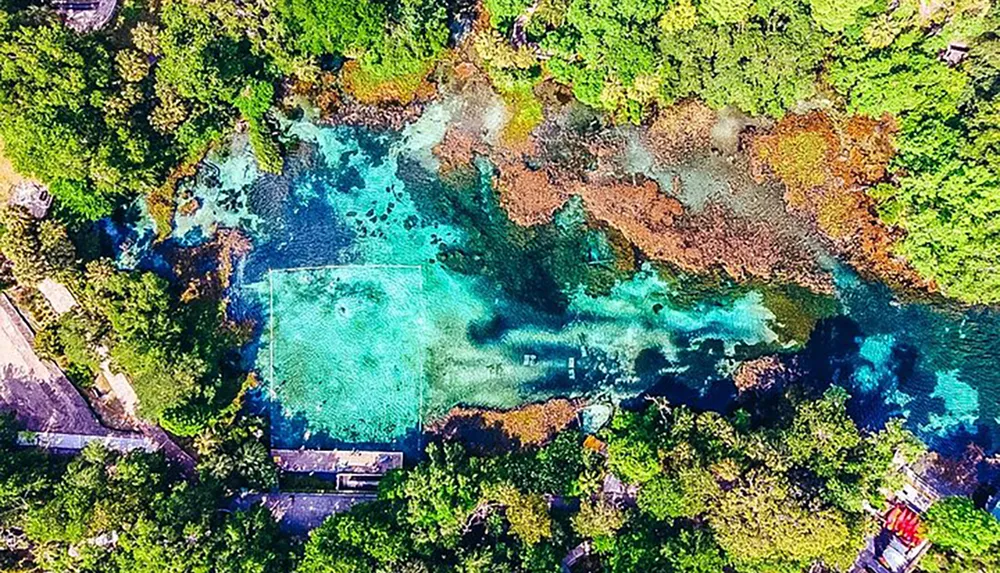 An aerial view captures the breathtaking colors of a tropical lagoon surrounded by lush foliage
