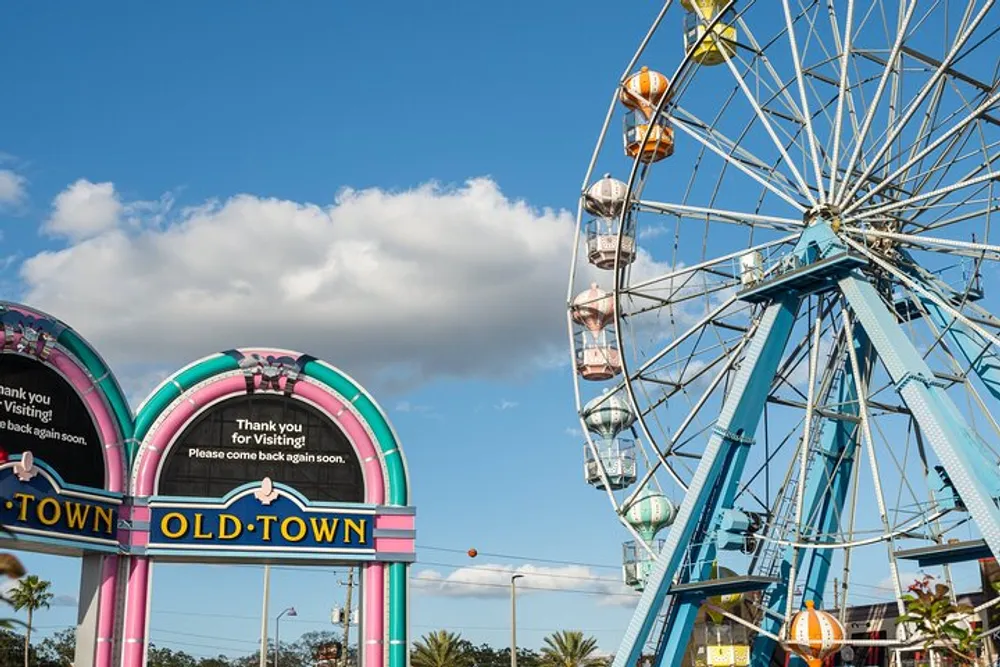 The image shows a colorful archway with the words OLD TOWN and a Ferris wheel against a partly cloudy sky