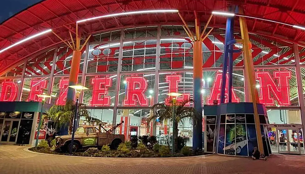 The image shows a vibrant entertainment complex at nighttime illuminated with red neon signage that spells Determent