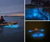 People are kayaking at dusk with illuminated kayaks that cast a blue glow on the water