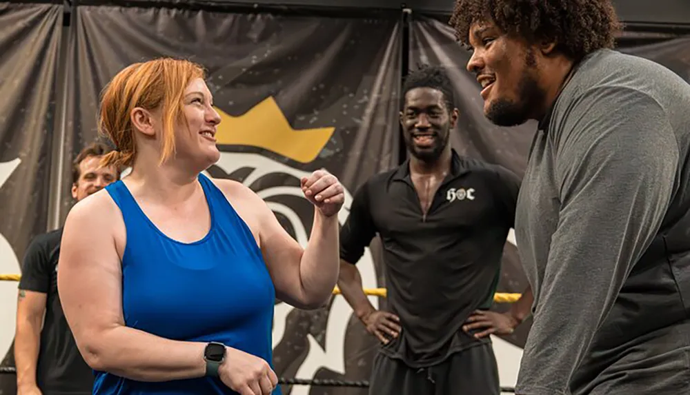 Two people appear to be having a friendly interaction or conversation with smiles on their faces while a third person in the background watches with a smile