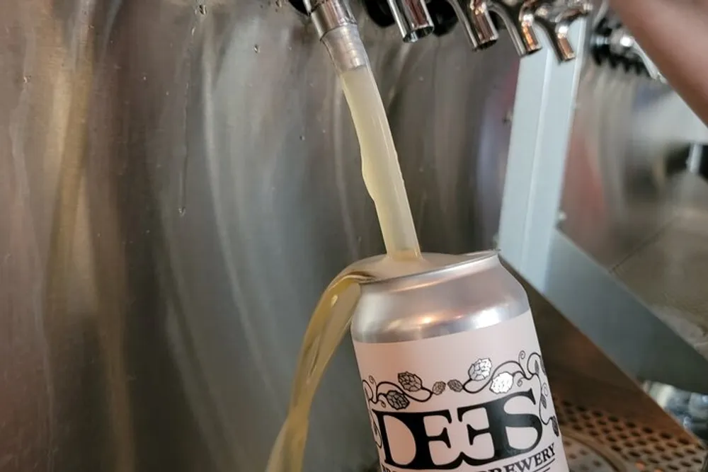 A can of beer is being filled directly from a tap at a brewery