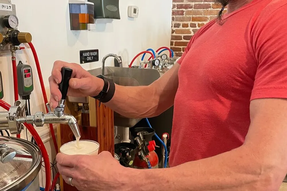 A person is pouring a draft beer from a tap into a glass at a brewery or bar