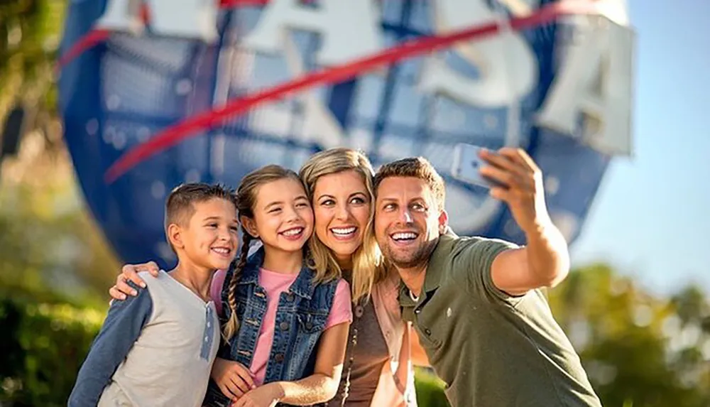 A happy family with two children is taking a selfie with a hot air balloon in the background