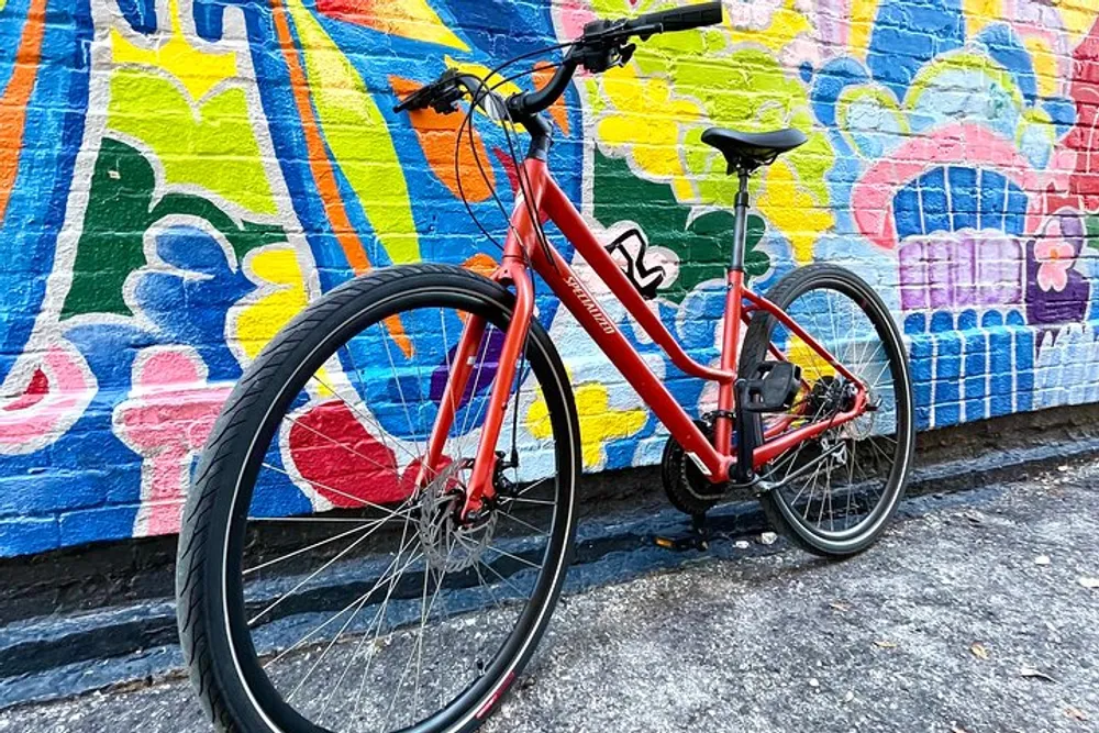 A red bicycle stands against a vibrant graffiti-covered wall