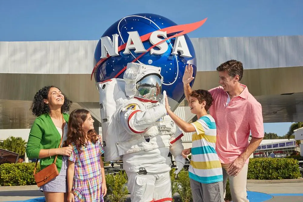 A family is having a fun interaction with a person in an astronaut suit in front of a large NASA insignia