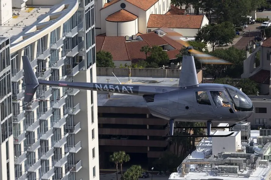 A small aircraft is flying closely between high-rise buildings in an urban area.