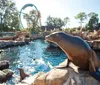 Two orcas are leaping out of the water in a synchronized performance with a backdrop that simulates a natural environment