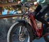 A person is riding a red electric bicycle equipped with a basket and a headlight