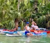 A group of people are enjoying paddleboarding and kayaking amidst lush greenery in a clear water stream