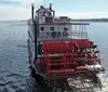 A traditional paddlewheel riverboat is cruising on calm waters under a clear sky