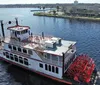 A traditional paddlewheel riverboat is cruising on calm waters under a clear sky