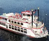 A traditional paddlewheel riverboat is cruising on calm waters under a clear sky