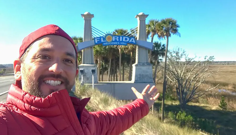 A person is taking a selfie with a welcome sign at the Florida state border