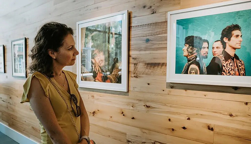 A woman is observing framed photographs in an art gallery with a wooden interior