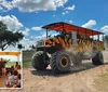 A large modified vehicle with massive tires and a tiger-striped body travels on a dusty road under a blue sky