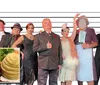 Seven people dressed in vintage formal attire stand in front of a height chart backdrop