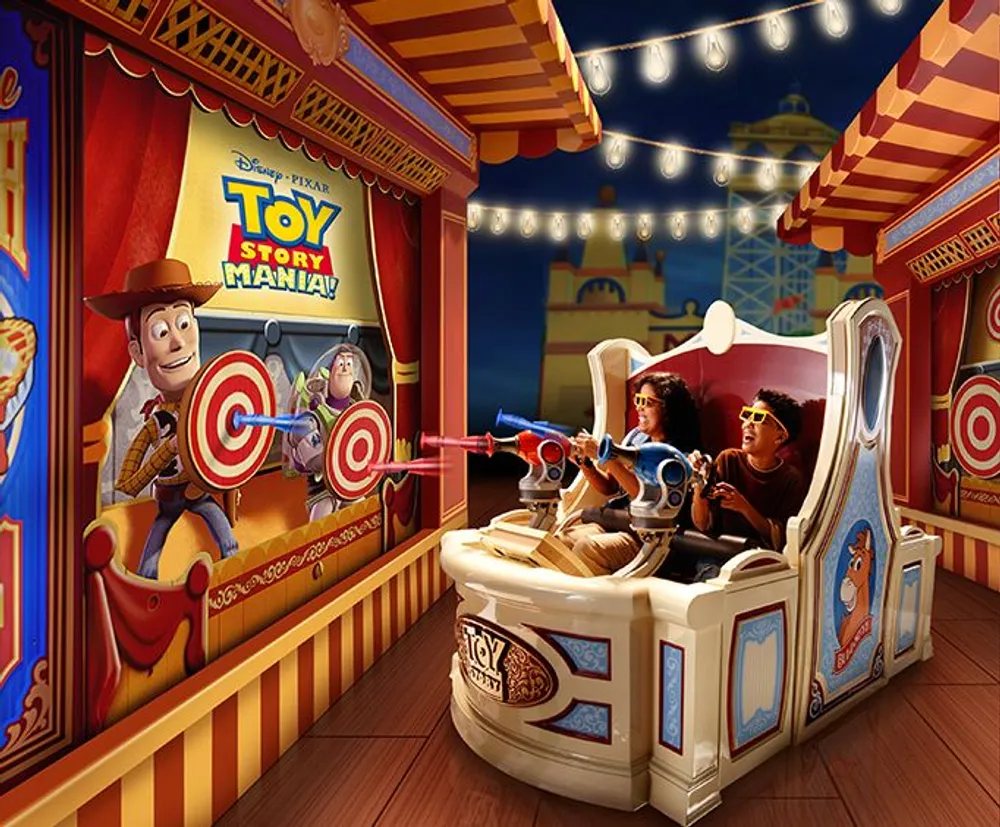 Two guests are enjoying the Toy Story Mania attraction shooting at virtual targets in a carnival-themed ride