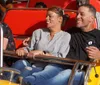 Thrilled passengers with raised arms are experiencing a steep drop on a wooden roller coaster under a clear sky