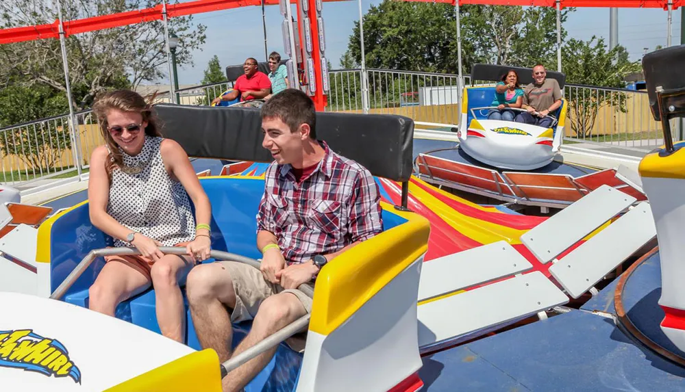 Visitors are enjoying a colorful spinning amusement park ride on a sunny day