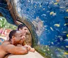 A person is smiling and enjoying a ride on a yellow inner tube down a vibrant blue water slide