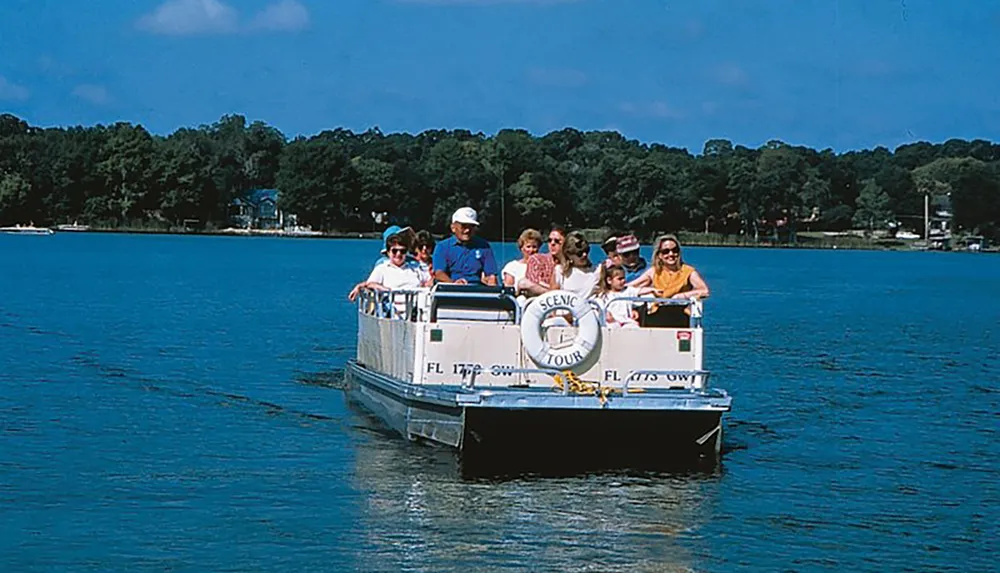 A group of people enjoys a scenic tour on a sunny day aboard a small boat gliding across calm blue waters