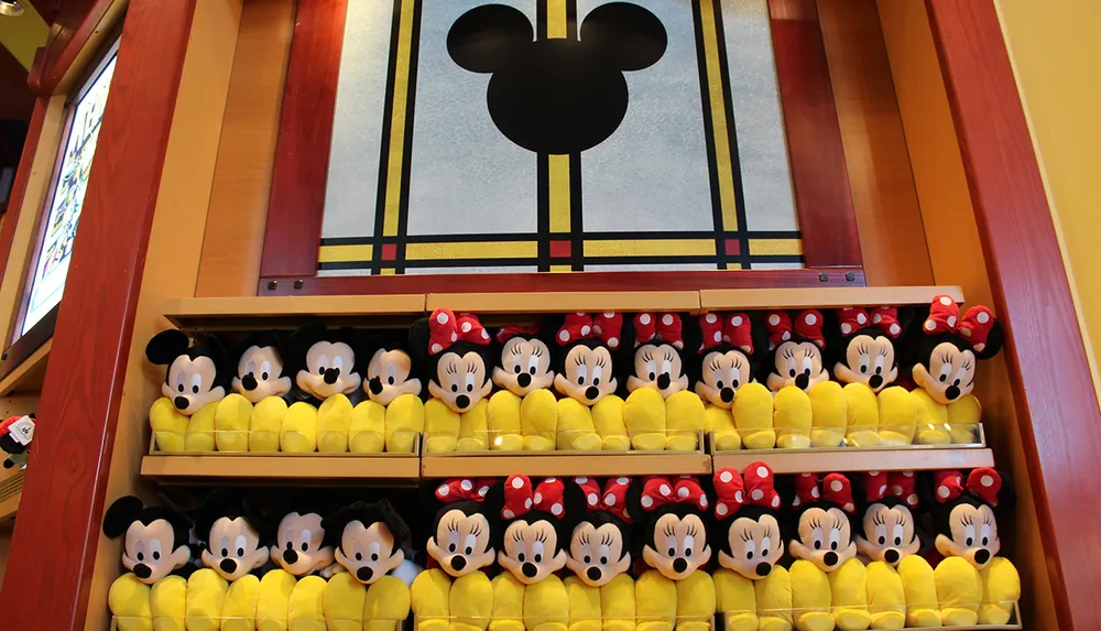 The image shows a collection of Mickey and Minnie Mouse plush toys arranged neatly below a large stained-glass window with the iconic silhouette of Mickey Mouses head