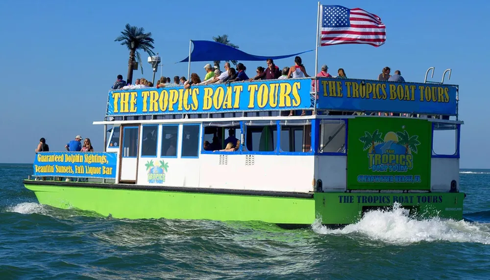 A tourist boat named The Tropics Boat Tours is sailing on the water with passengers on board enjoying the trip
